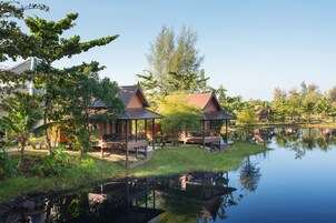 Un resort tranquilo junto al lago con cabañas de madera, un espacio con césped y un reflejo en el agua.