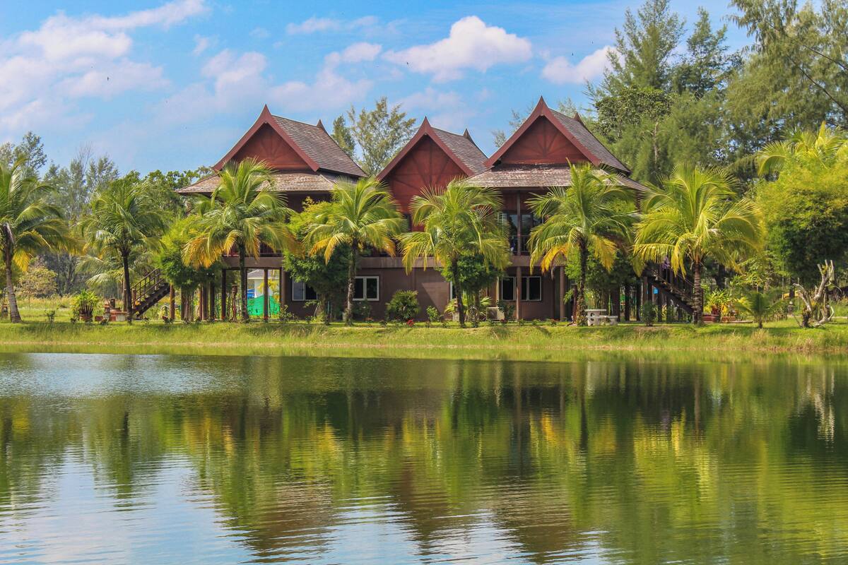 Een resort met meerdere gebouwen, een meer en palmbomen.