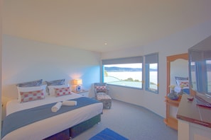 A bedroom with a large bed, a chair, a desk, and a view of the sea. - PierView Apartments (Lorne)