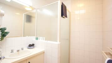 A bathroom with a sink, mirror, towel rack, and a shower area.