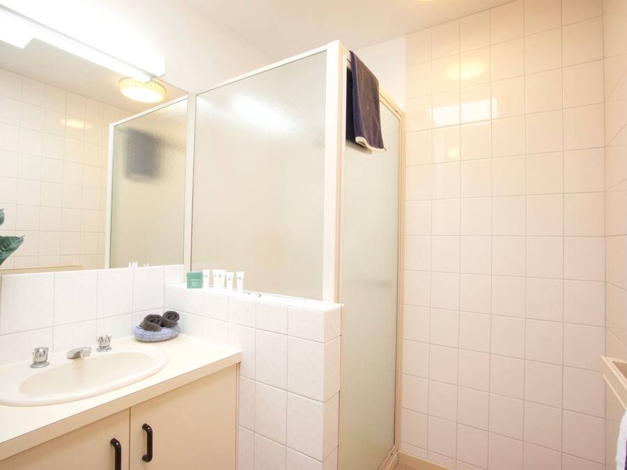 A bathroom with a sink, mirror, towel rack, and a shower area.