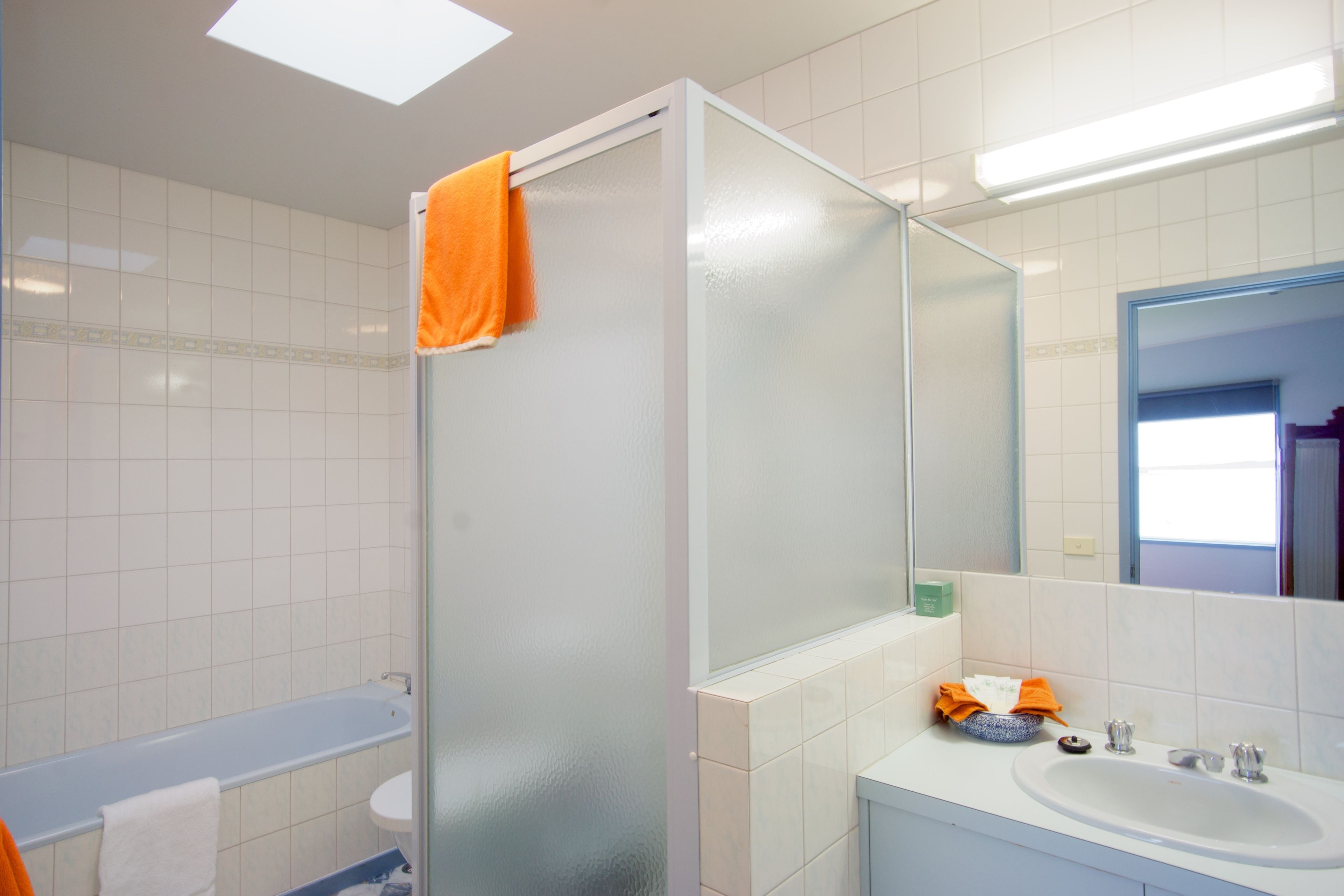 A bathroom with a glass shower enclosure, a white sink, and a mirror above the sink.