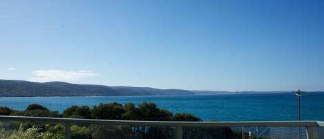 A coastal view with a clear sky, a body of water, and distant hills.