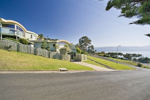 A row of beachfront houses with a wooden fence, a clear sky, and a view of the ocean. - PierView Apartments (Lorne)