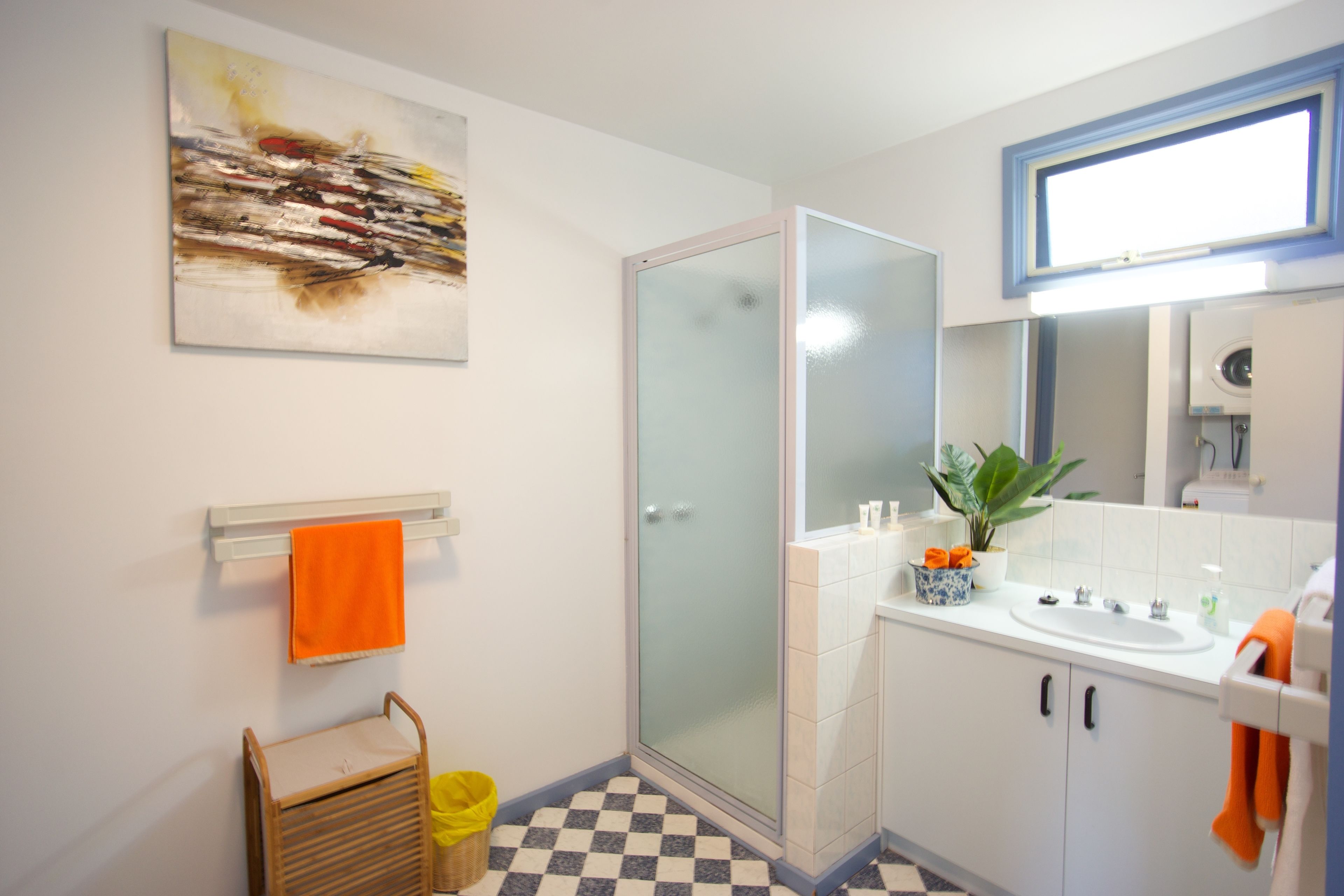 Un baño moderno con cabina de ducha de vidrio, un lavabo con espejo y suelo a cuadros.