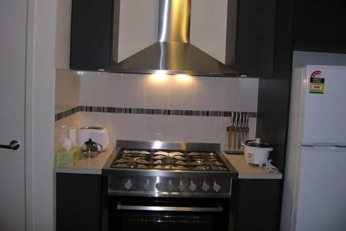 Een keuken met een gasfornuis, oven en een roestvrijstalen afzuigkap.