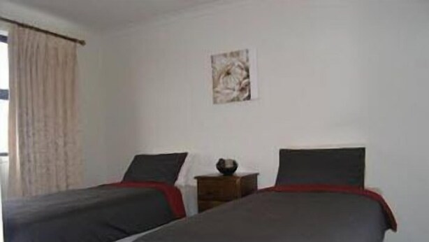 Een kamer met twee bedden, een tafeltje en een schilderij aan de muur.