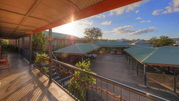 A covered outdoor area with multiple buildings, a paved ground, and a clear sky.