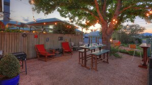 An outdoor patio area with wooden furniture, a table set for dining, and string lights. - The Vines Motel and Cottages (Stanthorpe)