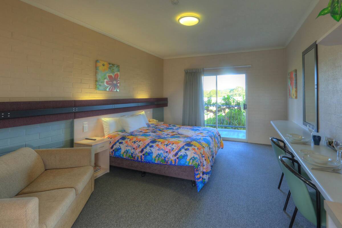 A hotel room with a bed, a sofa, a desk, and a bathroom.