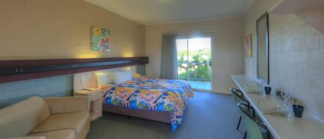 Een hotelkamer met een bed, een bank, een bureau en een badkamer.