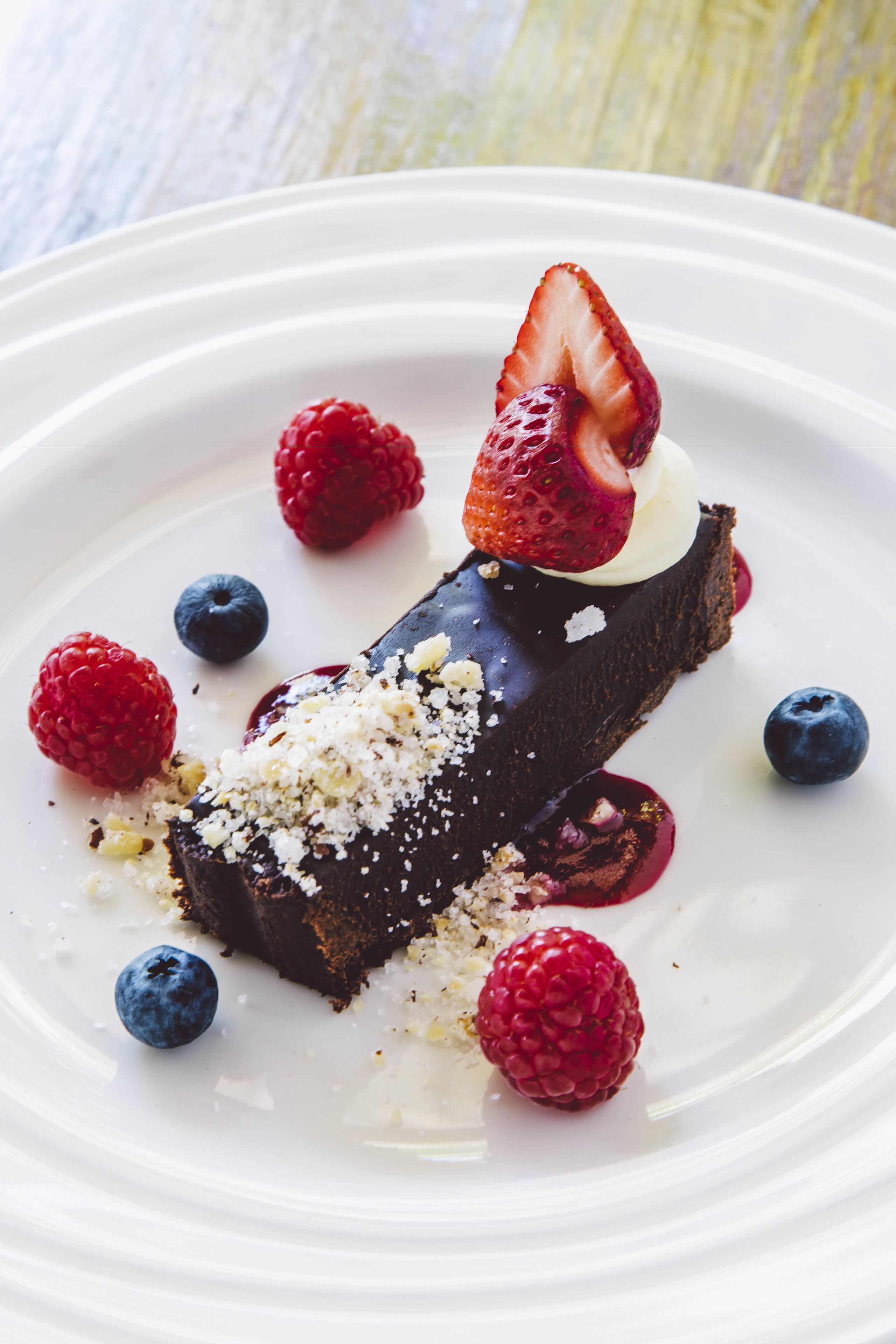 A dessert with chocolate, strawberries, and raspberries on a white plate.