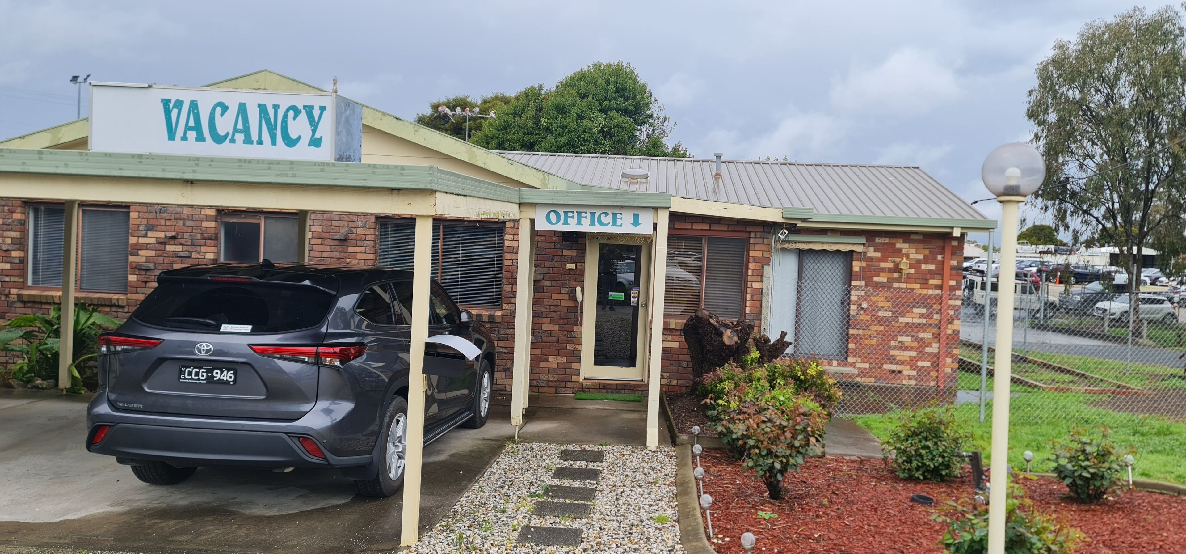 Un edificio con un cartel de 'VACANCY' y un letrero que dice 'OFFICE', además de un coche estacionado.