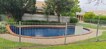 Una piscina al aire libre, sillones reclinables de piscina