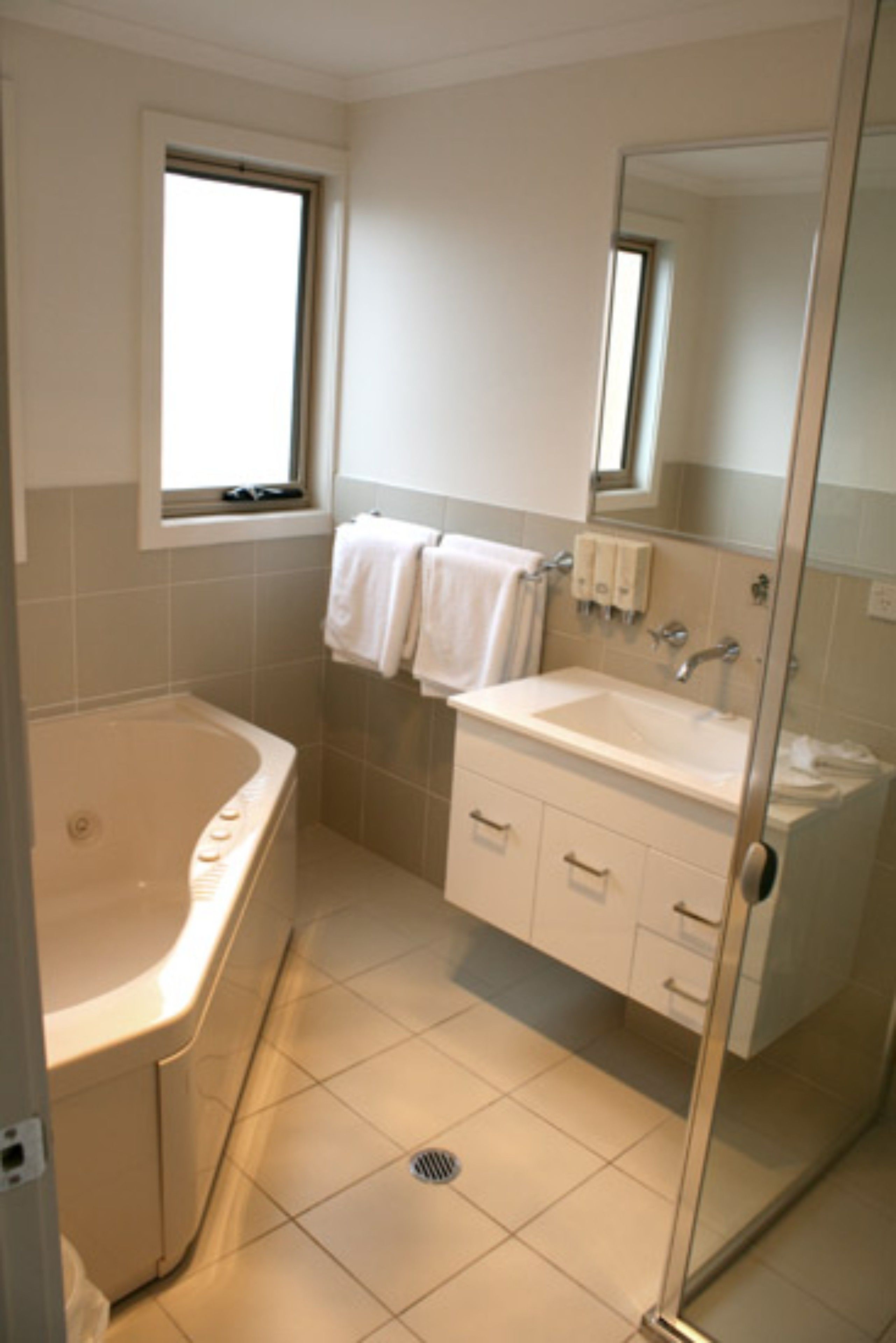 A modern bathroom with a bathtub, sink, and mirror.