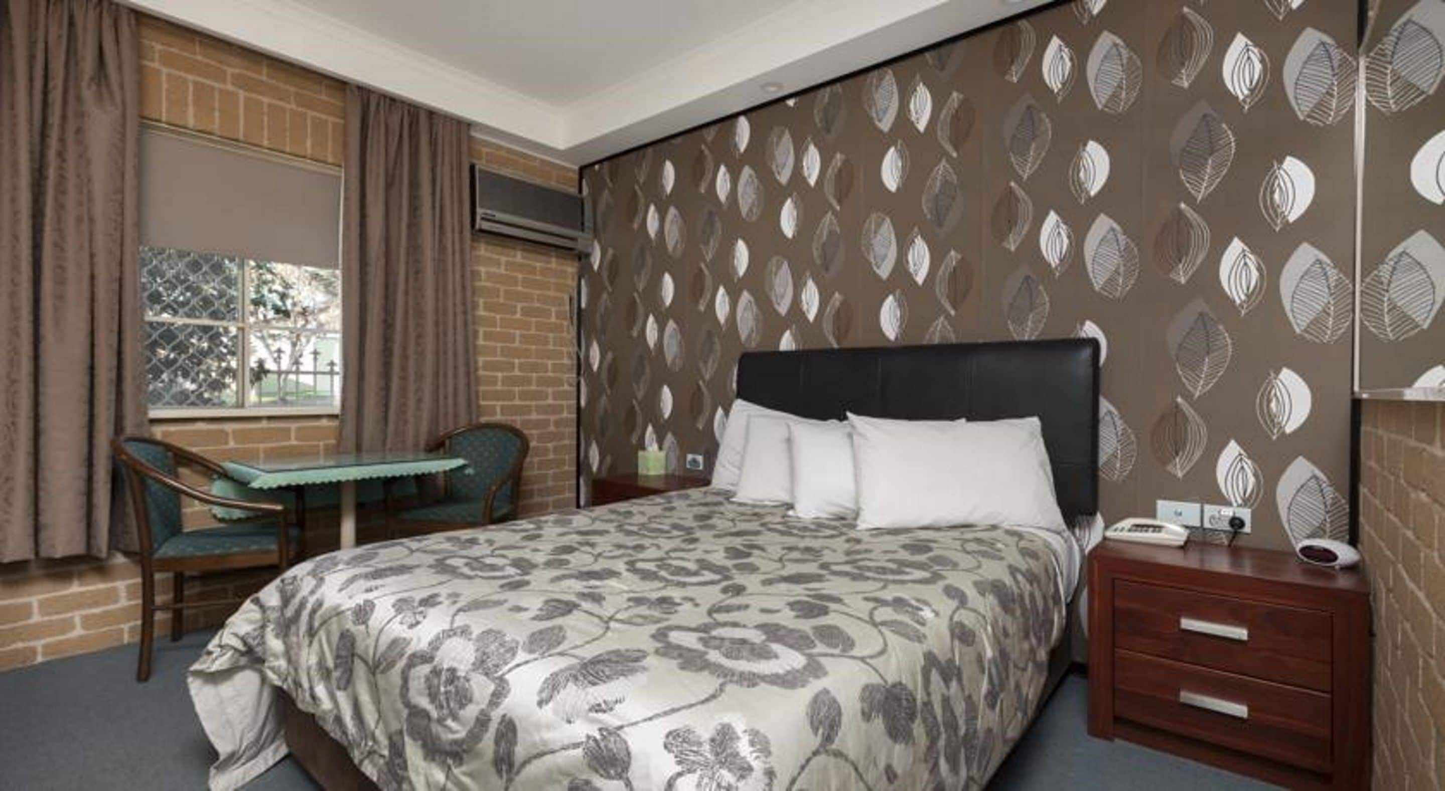 A hotel room with a large bed, a desk, and a chair.