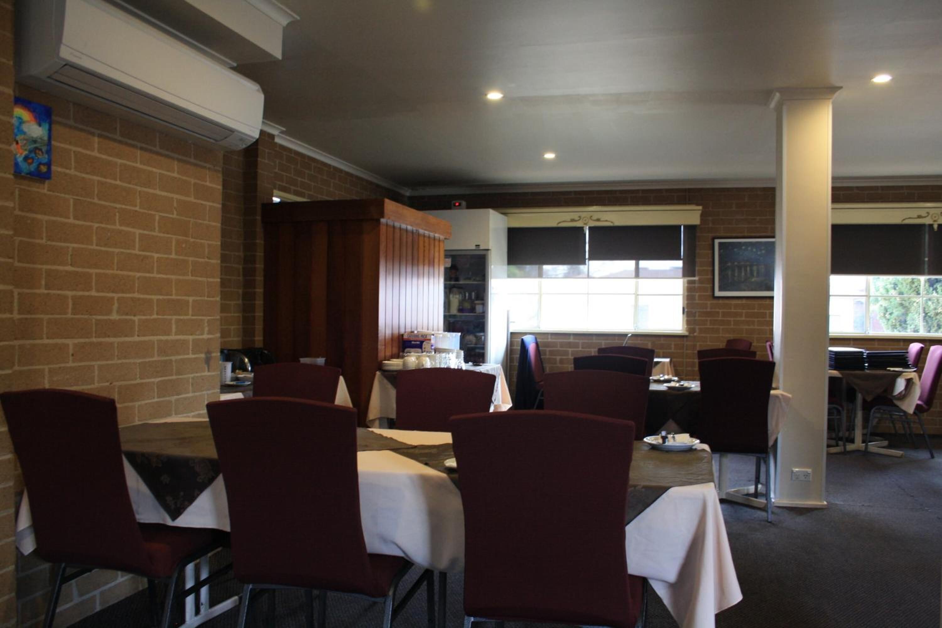 A restaurant with brick walls, multiple tables and chairs, and a window providing natural light.