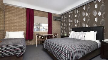 Two single beds with striped bedding, a small table, and two chairs are featured in this stylish room.