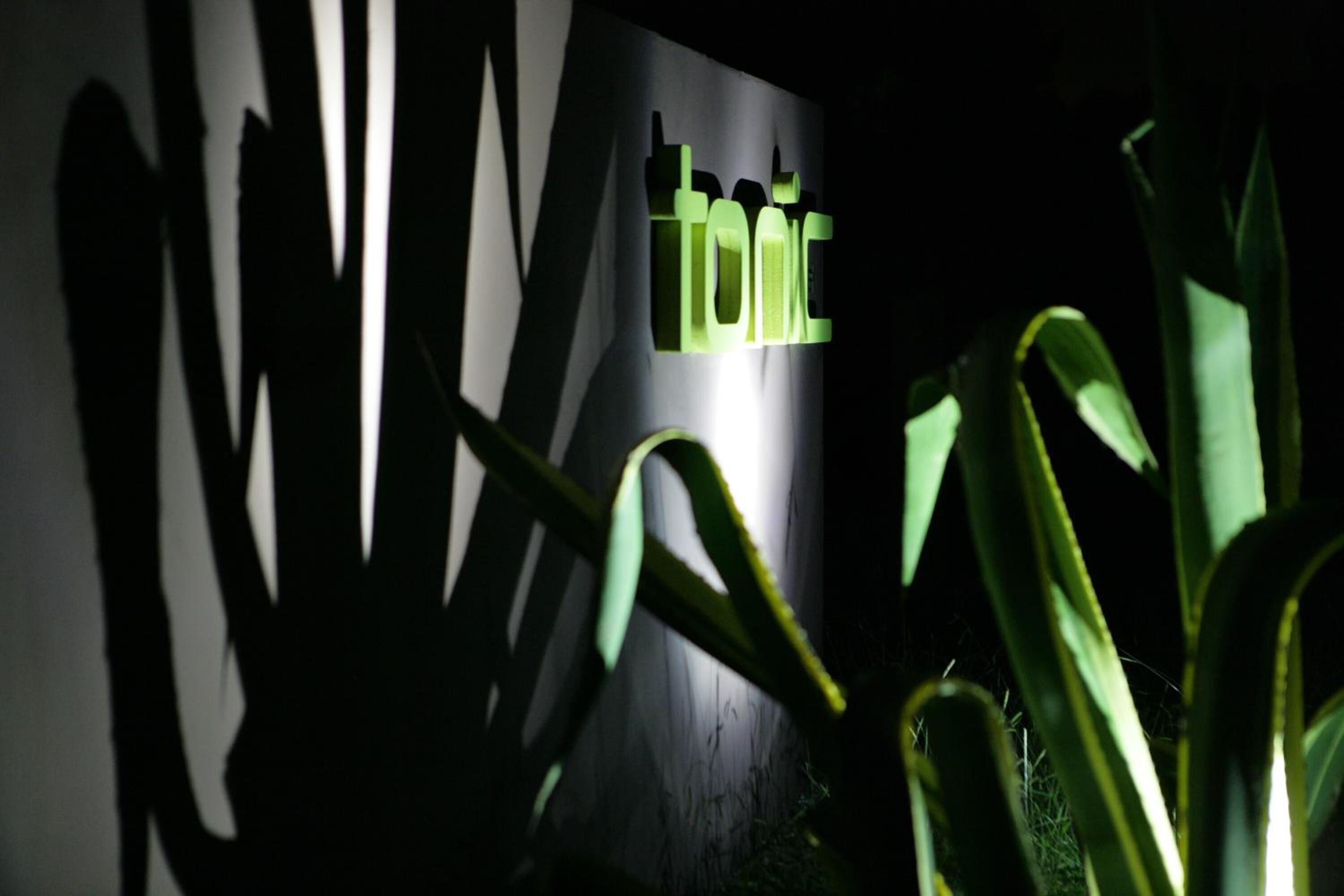 A wall with the word "tonic" illuminated in green letters.
