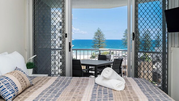 A balcony with a bed, a table, and chairs. - Rainbow Bay Resort (Coolangatta)