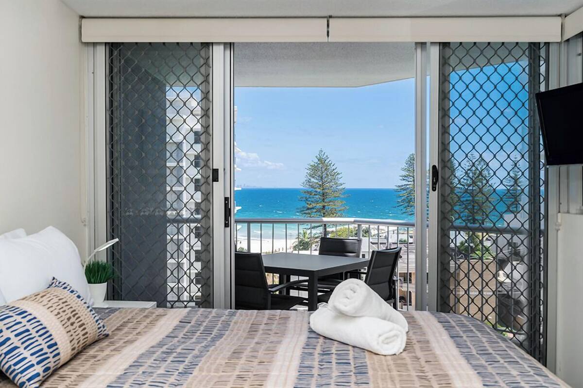 A balcony with a bed, a table, and chairs.