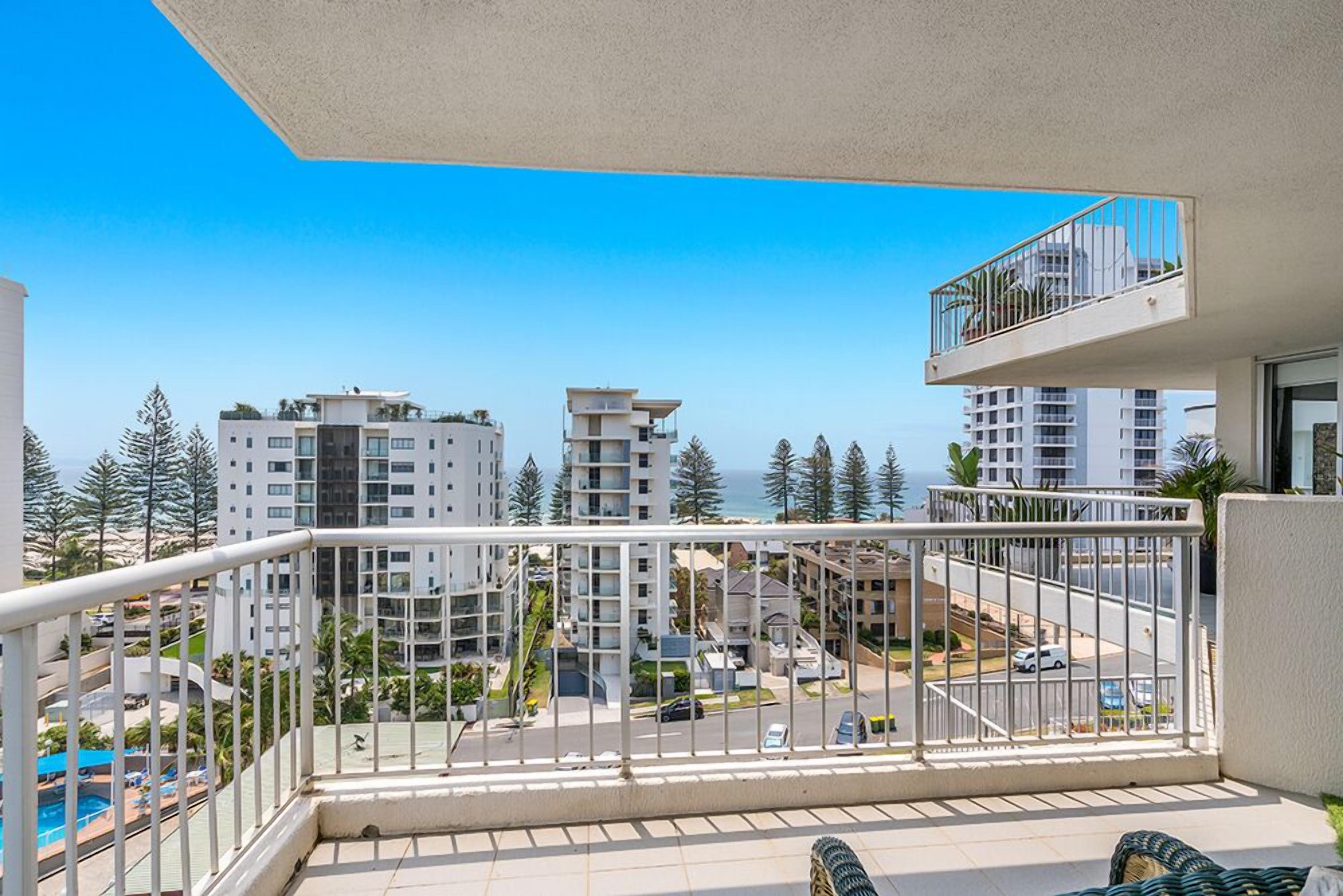 Un balcón con vista a una zona residencial, con edificios y una calle.