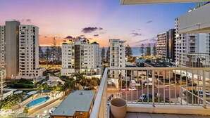 A high-rise building with multiple balconies, a swimming pool, and a view of the ocean at sunset. - Rainbow Bay Resort (Coolangatta)