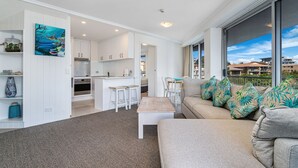 A modern living room with a sofa, a dining area, and a kitchen. - Rainbow Bay Resort (Coolangatta)