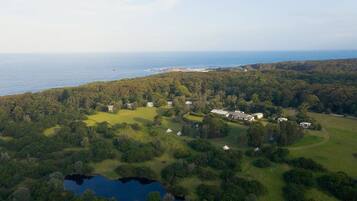 Stunning estate surrounded by lush greenery and a large body of water, offering scenic views of the sea.
