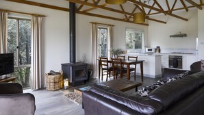 A living room with a fireplace, sofa, and dining area. - Mystery Bay Cottages (Mystery Bay)