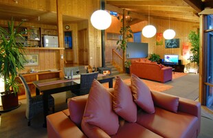 Um interior acolhedor em madeira, com sofá, mesa de jantar e televisão.