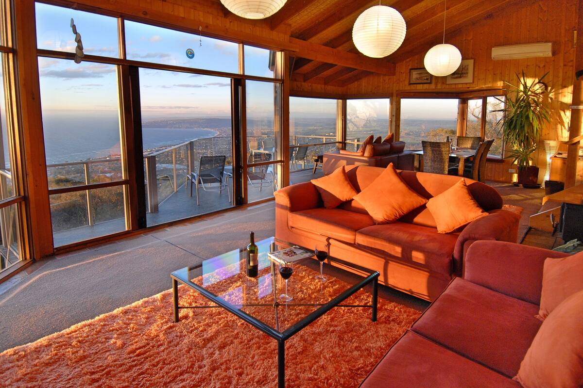 A spacious living area with a large window offering a panoramic view of the city and ocean.