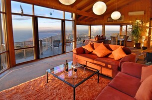 Ampla sala de estar com uma grande janela que oferece uma vista panorâmica da cidade e do oceano.