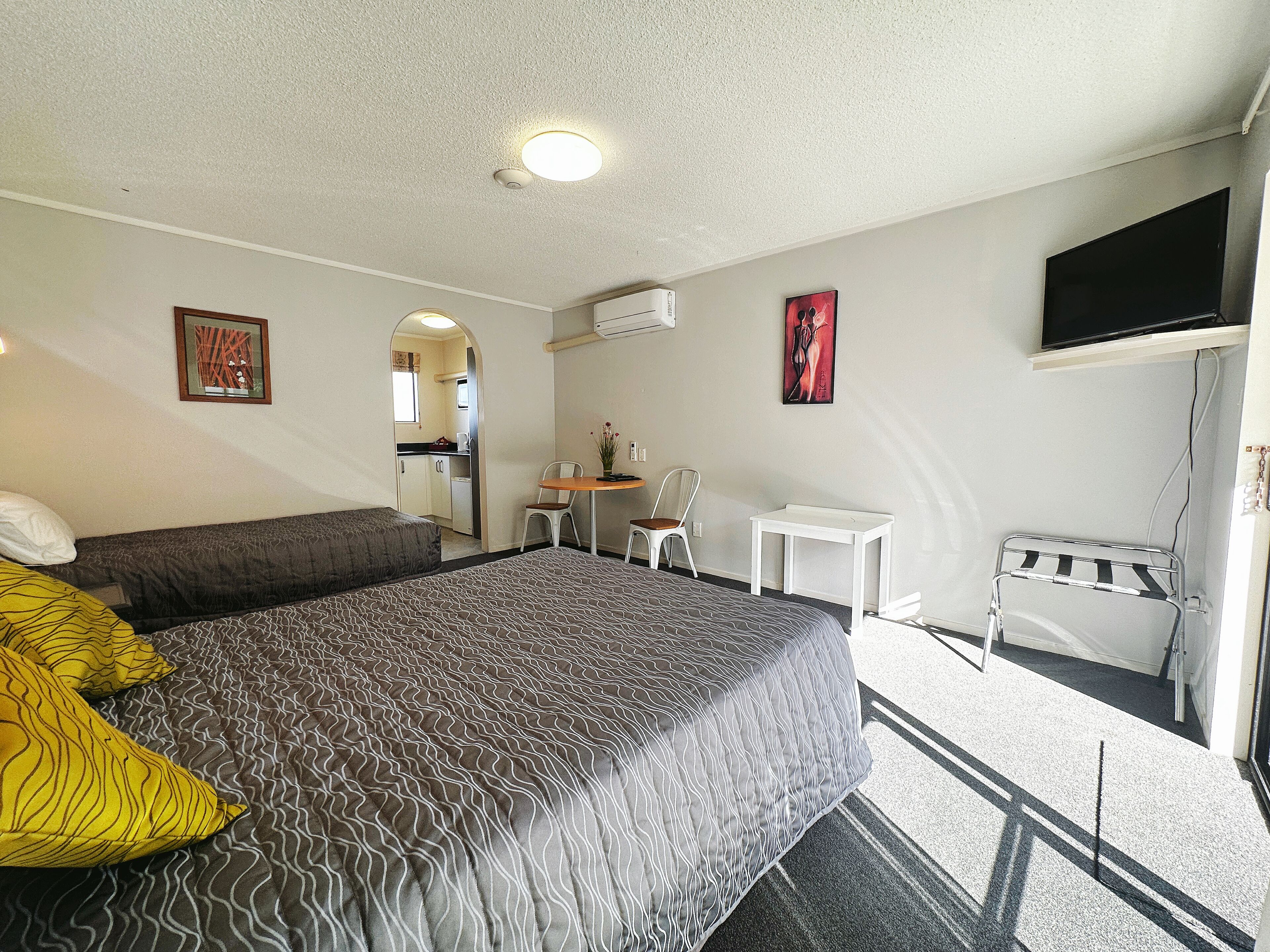 Een hotelkamer met een bed, een bureau, een stoel, een televisie en een klein balkon.
