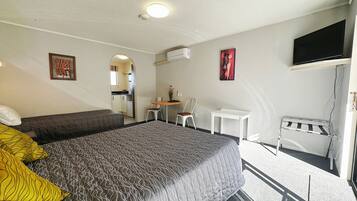 Een hotelkamer met een bed, een bureau, een stoel, een televisie en een klein balkon.