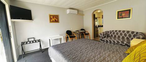 Een hotelkamer met een bed, een bureau, een stoel, een televisie en een kitchenette.