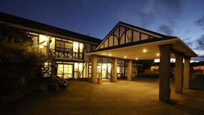 A building with a covered entrance and large windows, likely a hotel or similar accommodation. - Kingswood Manor Motel (Whangarei)