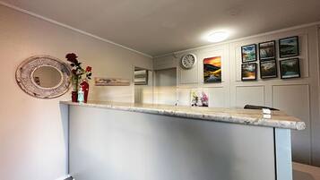 Una cocina con encimera de mármol, un reloj y cuadros en la pared.