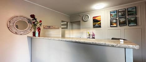 Una cocina con encimera de mármol, un reloj y cuadros en la pared.