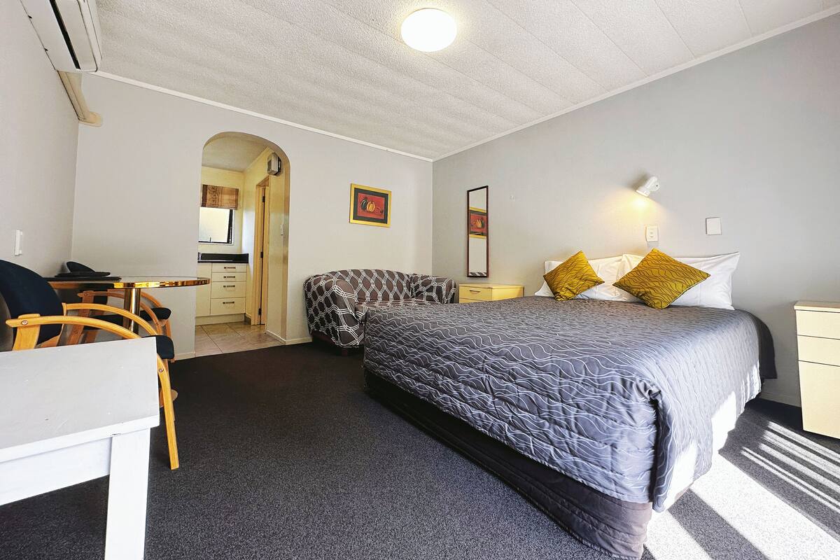 A bedroom with a bed, bedside table, and a desk with a chair.