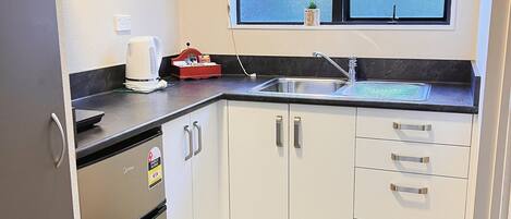 A compact kitchen with a built-in refrigerator, a sink, and a window with a view.