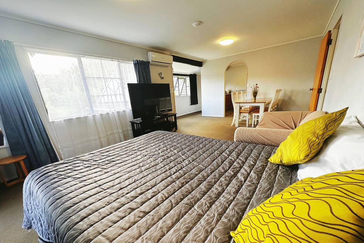 A hotel room with a large bed, a desk, a chair, and a TV.