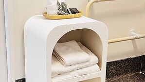 A white, arched cat bed with a tray on top, placed next to a bathtub in a bathroom. - AAA Northlands Motel (Christchurch)