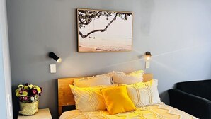 A bedroom with a bed, bedside tables, a wall-mounted picture, and a nightstand with a vase of flowers. - AAA Northlands Motel (Christchurch)