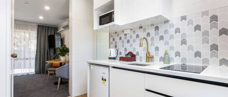 A modern kitchen with white cabinetry, a black countertop, and a herringbone tile backsplash.