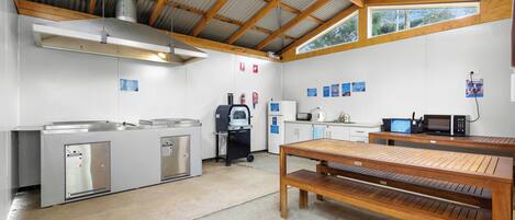A kitchen with stainless steel appliances, a wooden table, and a ceiling fan.