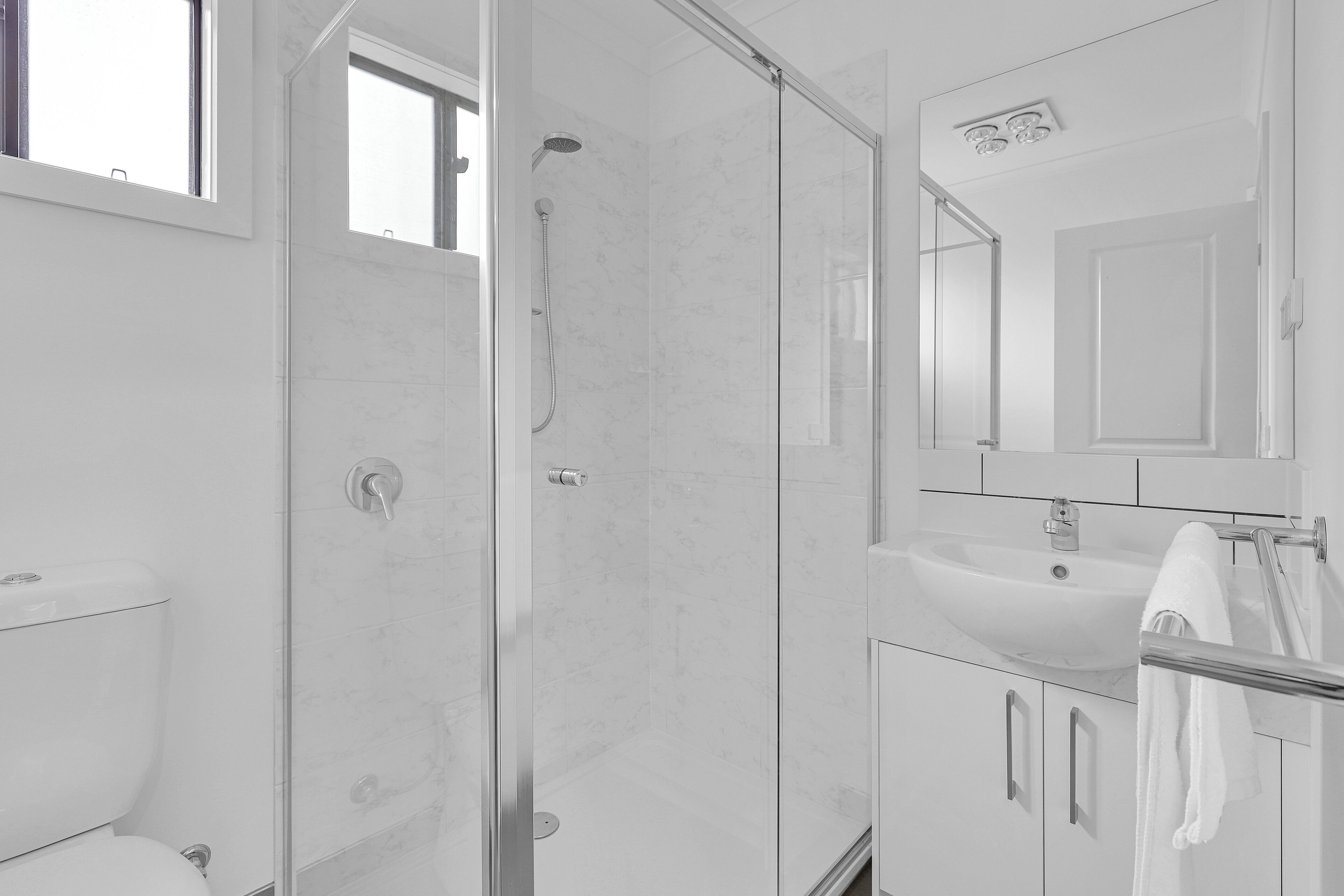 Un bagno moderno con doccia vetrata, lavandino bianco e specchio sopra il lavandino.