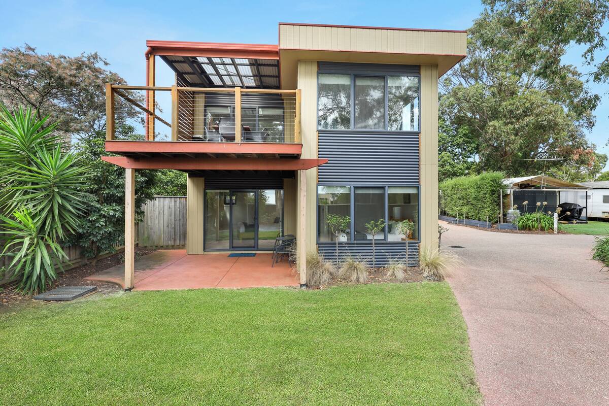 A modern two-story house with a balcony, a garage, and a well-maintained lawn.