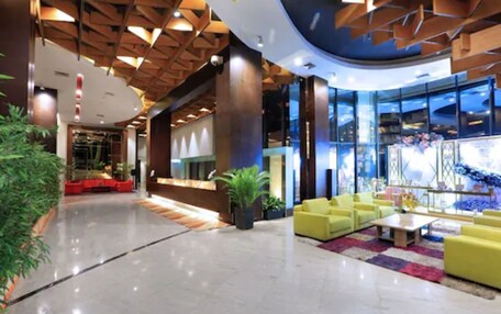 A modern lobby with a curved ceiling, a reception desk, yellow seating area, and a large window with a view.