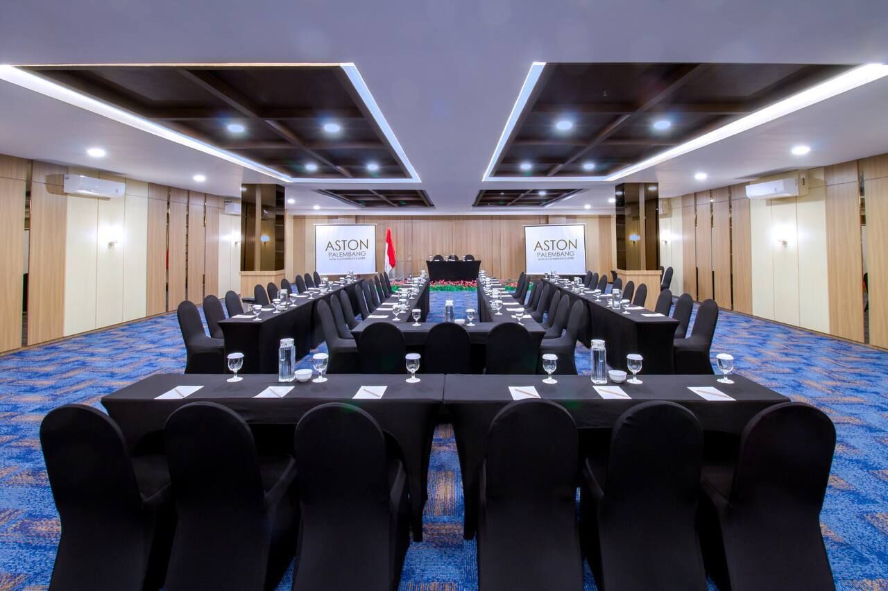 A conference room with long tables, black chairs, and a podium.